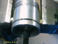 Holding a piston in the vice using two nuts as spacers to prevent damage.